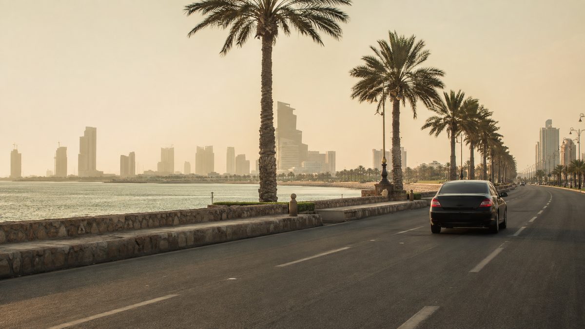 A palm-lined corniche road along the Red Sea in Jeddah in hazy afternoon light