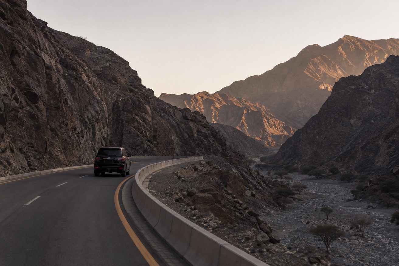 A road winding through dark rocky mountains between the UAE and Oman