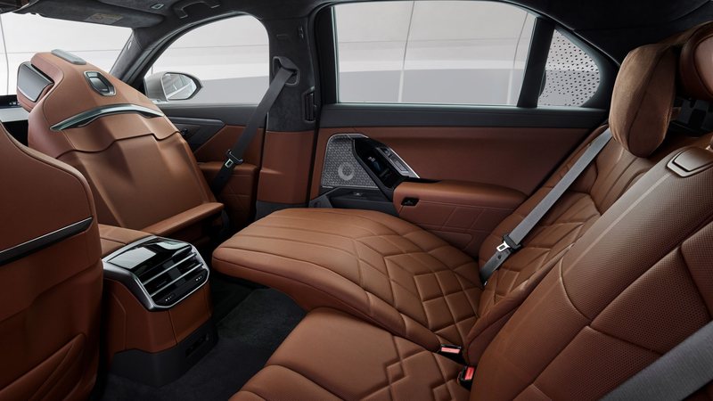 The rear seat of a BMW 7 Series fully reclined with the footrest extended, the ceiling screen stowed, in tan leather.
